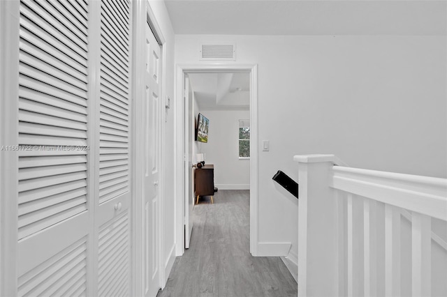 corridor featuring baseboards, an upstairs landing, wood finished floors, and visible vents