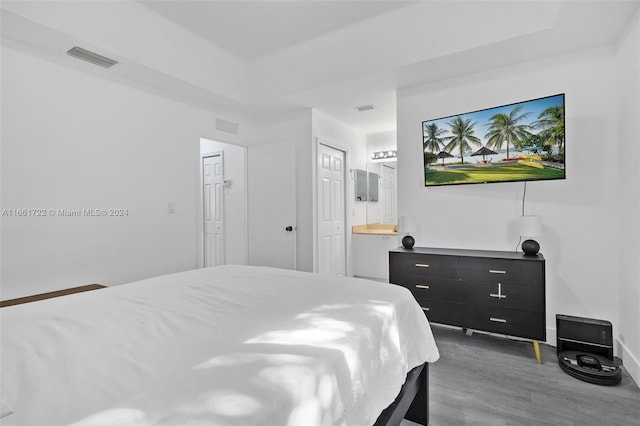 bedroom with ensuite bath and dark hardwood / wood-style flooring