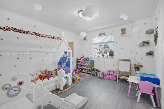 rec room featuring hardwood / wood-style flooring, ornamental molding, and a textured ceiling