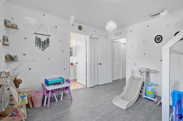 rec room with ornamental molding and light wood-type flooring