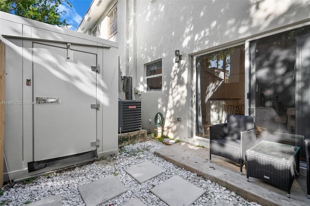 view of exterior entry featuring central AC unit, a patio area, and stucco siding