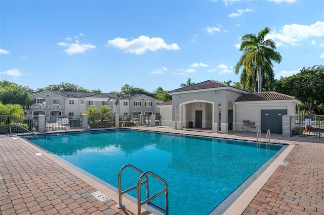 community pool featuring a patio, fence, and a residential view