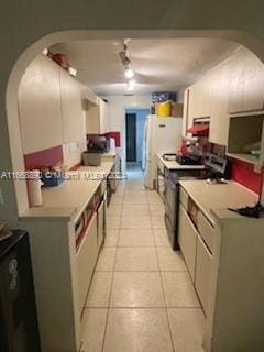 kitchen featuring light tile patterned floors, white fridge, and stainless steel range oven