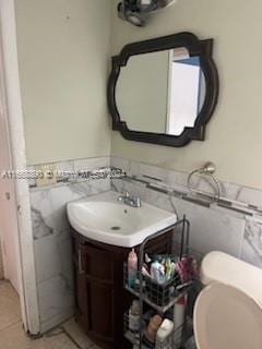 bathroom with tile walls, tile patterned flooring, vanity, and toilet