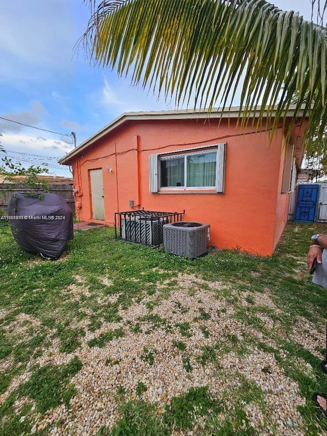 view of side of home featuring cooling unit and a yard