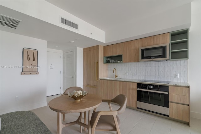 kitchen with light stone counters, sink, stainless steel appliances, backsplash, and light tile patterned floors