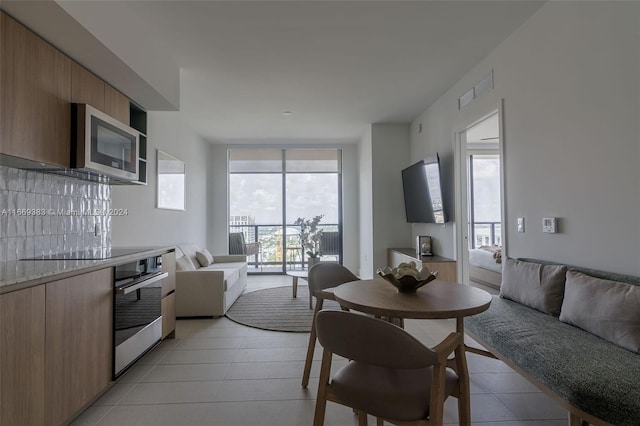 interior space with appliances with stainless steel finishes, light tile patterned floors, and decorative backsplash