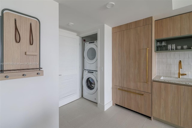 laundry room with stacked washer and dryer and sink