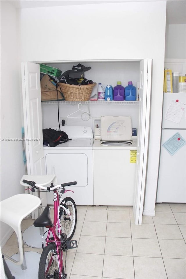 clothes washing area with light tile patterned floors and washer and dryer