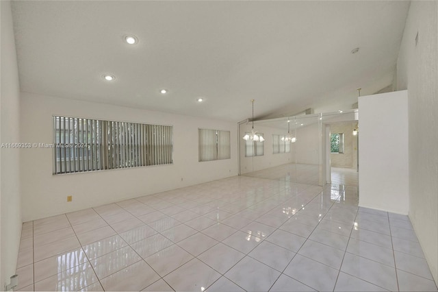 tiled empty room with a notable chandelier and lofted ceiling