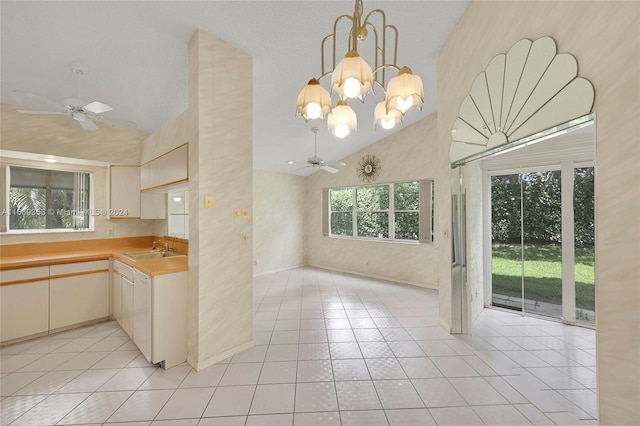 kitchen with ceiling fan with notable chandelier, pendant lighting, high vaulted ceiling, and light tile patterned floors