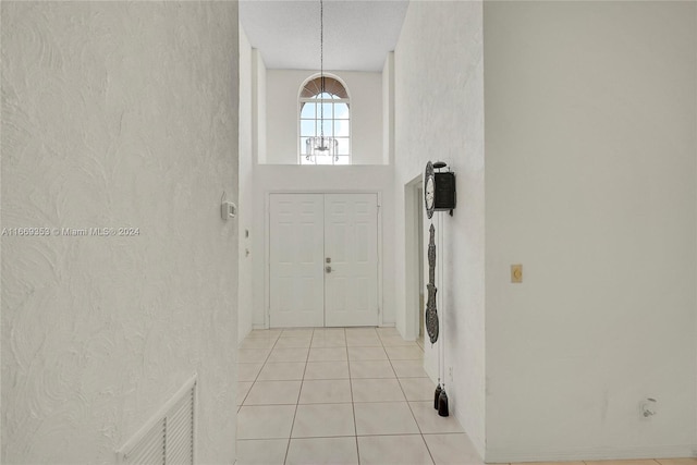 entryway featuring a high ceiling, a textured ceiling, and light tile patterned flooring