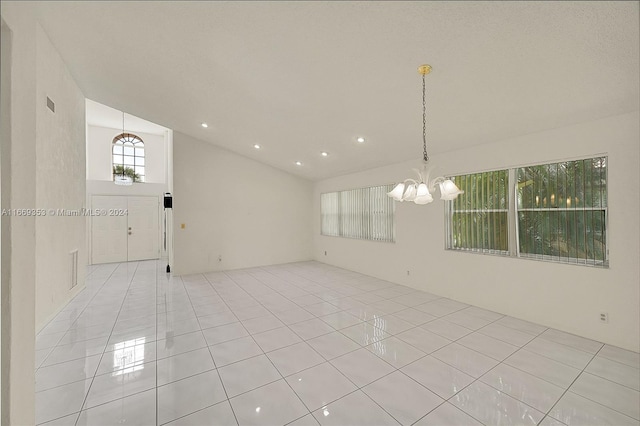 tiled empty room with an inviting chandelier and lofted ceiling