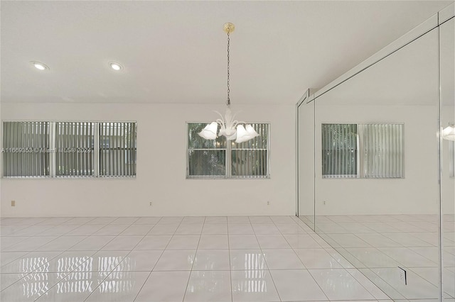 spare room with light tile patterned flooring and a chandelier