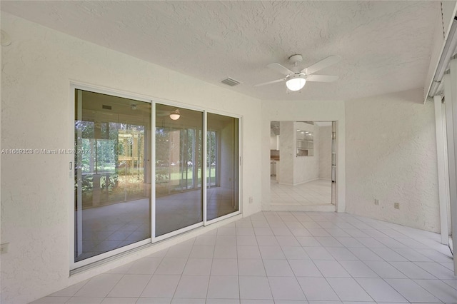 unfurnished room featuring ceiling fan, light tile patterned floors, and a textured ceiling