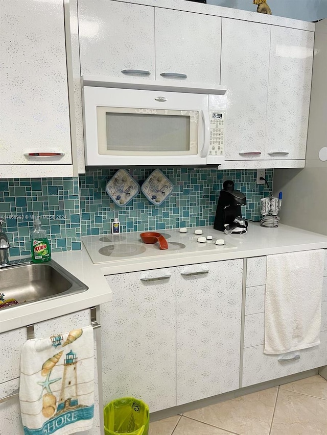 kitchen featuring white cabinetry, sink, light tile patterned floors, and tasteful backsplash