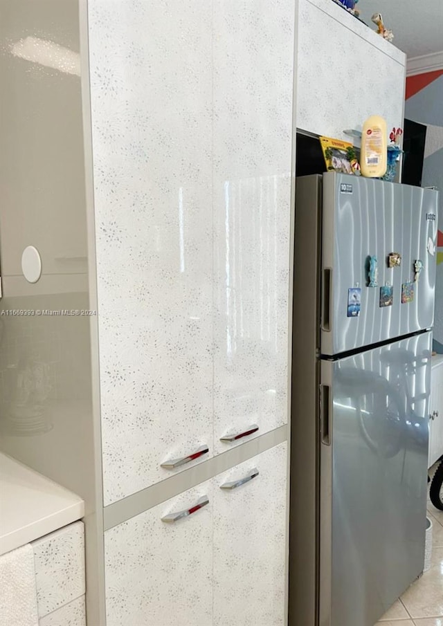 interior space with stainless steel fridge, light tile patterned floors, and crown molding