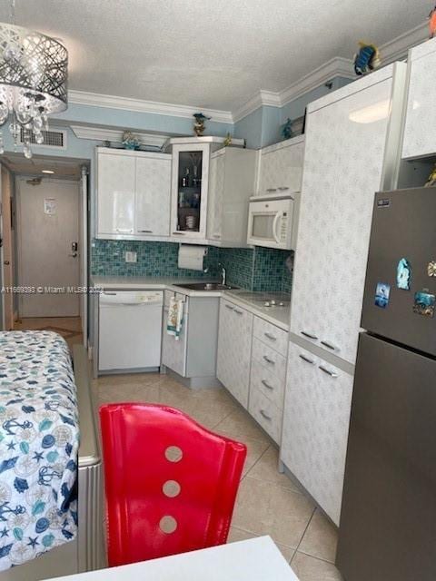 kitchen featuring tasteful backsplash, ornamental molding, white appliances, light countertops, and light tile patterned flooring