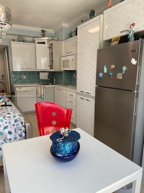 kitchen featuring ornamental molding, decorative backsplash, and white appliances