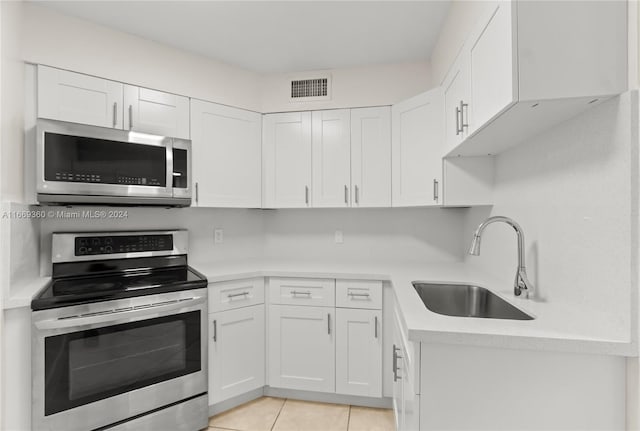 kitchen featuring sink, light tile patterned floors, stainless steel appliances, and white cabinets