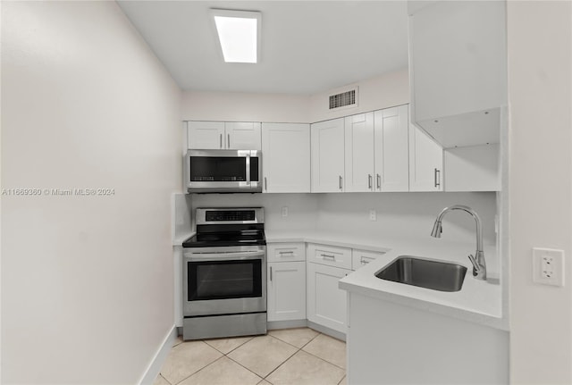 kitchen with light tile patterned floors, white cabinets, stainless steel appliances, and sink