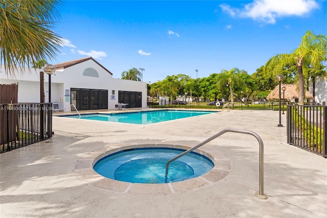 view of swimming pool featuring a hot tub and a patio area