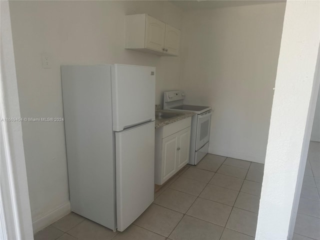 kitchen with light tile patterned floors, white appliances, and white cabinetry