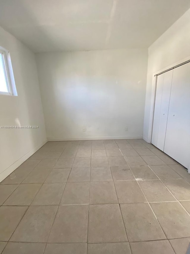 unfurnished bedroom featuring light tile patterned flooring and a closet