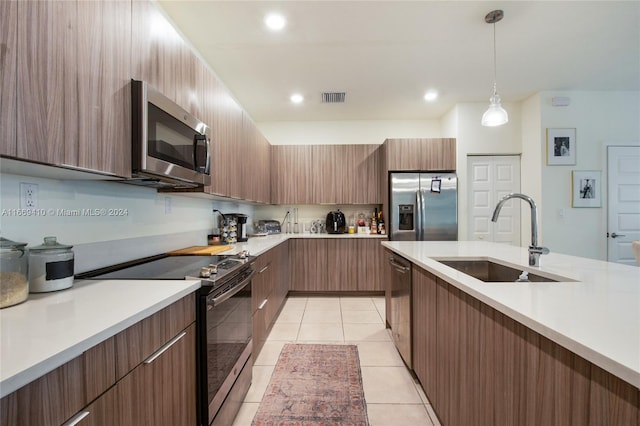 kitchen featuring appliances with stainless steel finishes, sink, light tile patterned floors, and decorative light fixtures