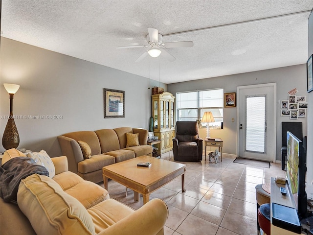 living room featuring ceiling fan, light tile patterned flooring, and a textured ceiling