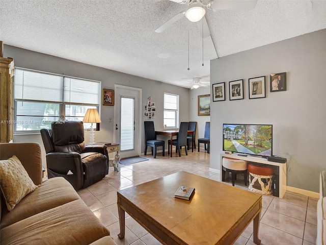 living room featuring ceiling fan, light tile patterned floors, and a textured ceiling