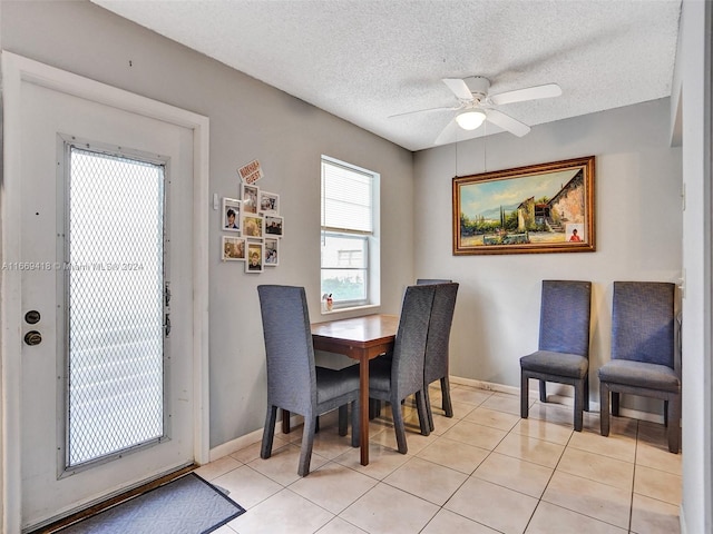 dining space with ceiling fan, a textured ceiling, and light tile patterned floors