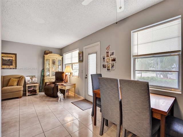 tiled dining area with ceiling fan and a textured ceiling