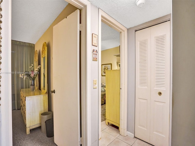 corridor with a textured ceiling and light tile patterned floors