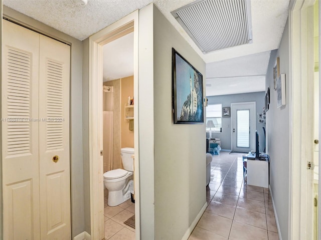 hallway featuring a textured ceiling and light tile patterned floors