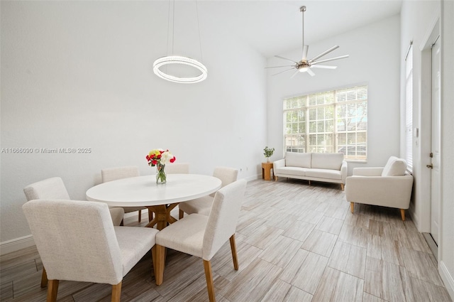 dining space with ceiling fan and high vaulted ceiling