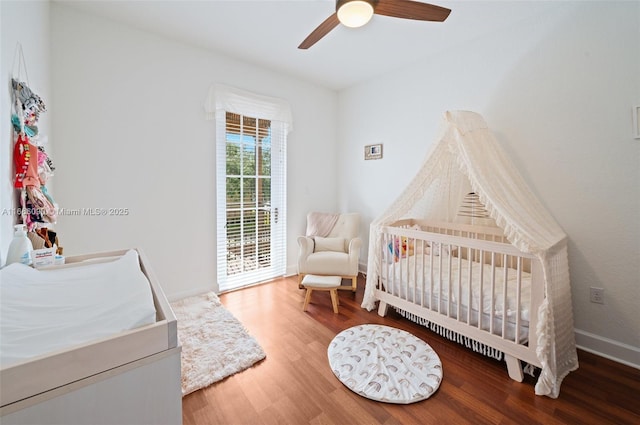 bedroom featuring a crib, hardwood / wood-style floors, and ceiling fan