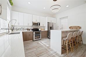 622 SW 147th Ter, Pembroke Pines, FL 33027 - kitchen featuring stainless steel appliances, a breakfast bar, light countertops, recessed lighting, and white cabinets