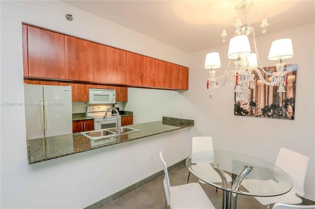 kitchen with dark stone counters, a notable chandelier, kitchen peninsula, hanging light fixtures, and white appliances