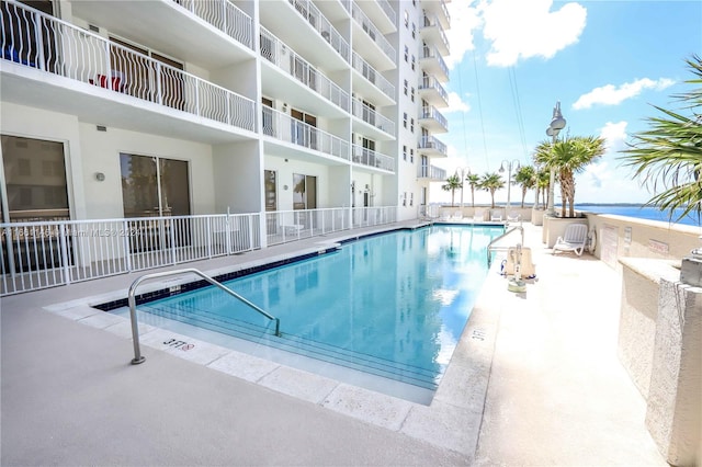 view of pool with a patio and a water view