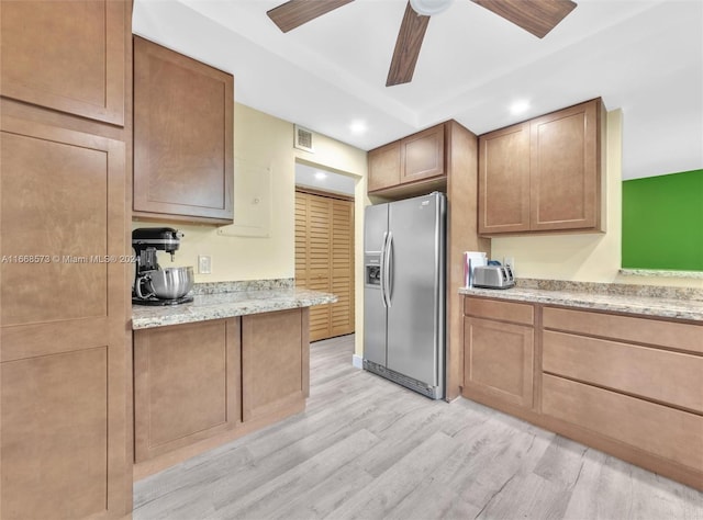 kitchen with ceiling fan, stainless steel fridge, light stone countertops, and light wood-type flooring