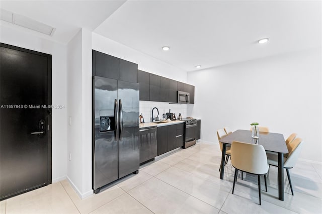 kitchen with decorative backsplash, sink, light tile patterned floors, and stainless steel appliances