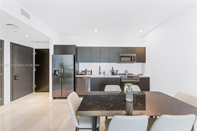 kitchen featuring decorative backsplash, stainless steel appliances, light tile patterned floors, and sink