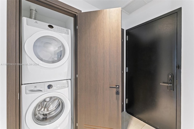 laundry area featuring stacked washing maching and dryer and light tile patterned floors