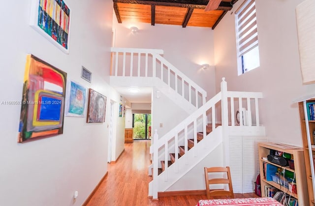 stairway with beamed ceiling, hardwood / wood-style flooring, high vaulted ceiling, and wooden ceiling