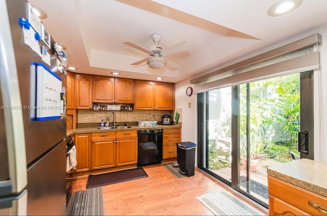 kitchen featuring black dishwasher, tasteful backsplash, stainless steel refrigerator, light hardwood / wood-style floors, and sink