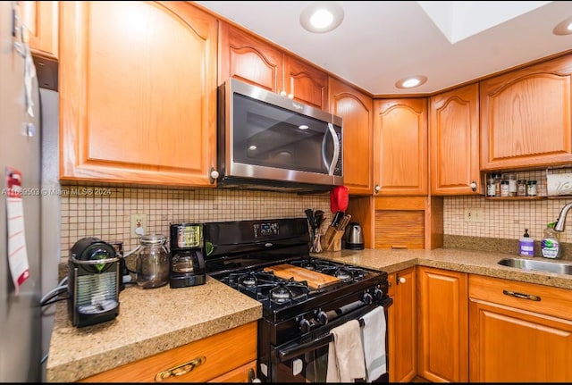 kitchen featuring sink, black range with gas stovetop, light stone countertops, and tasteful backsplash