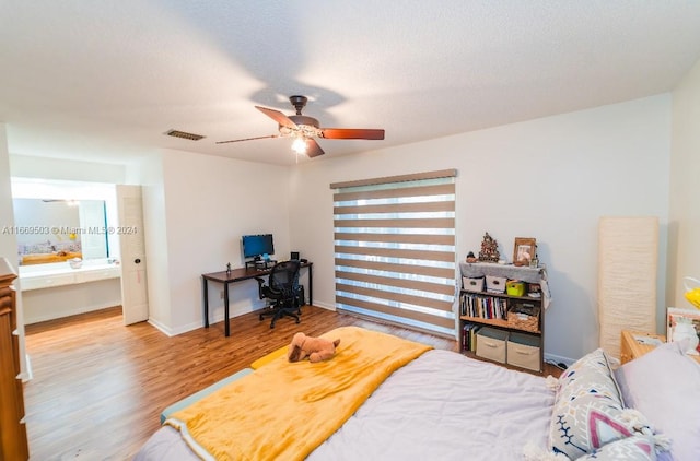 bedroom with ceiling fan, wood-type flooring, and a textured ceiling