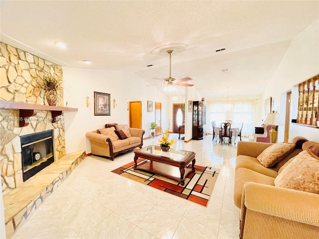 living room featuring ceiling fan, a textured ceiling, a fireplace, and vaulted ceiling