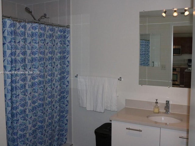 full bath featuring tiled shower and vanity